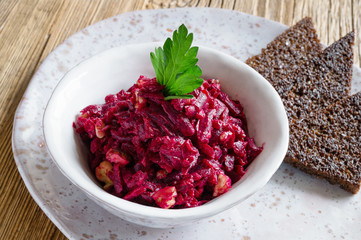 beetroot, walnuts, and garlic salad dressed with mayonnaise, decorated with parsley, and served with fried rye bread on a plate