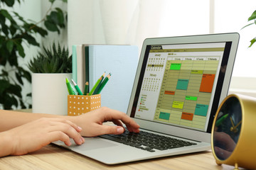 Woman using calendar app on laptop in office, closeup