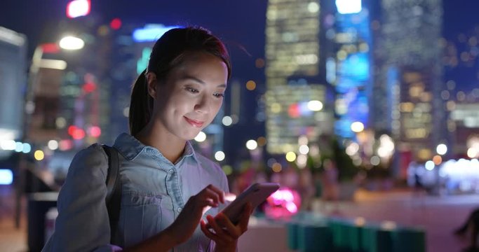 Woman check on cellphone in city at night