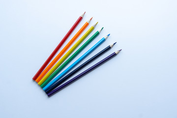 Set of seven sharp rainbow-colored pencils from top view on a white background. Concept of...
