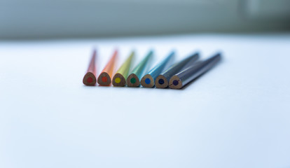 Set of seven not sharpened rainbow-colored pencils on a white background. Selective focus. Concept...