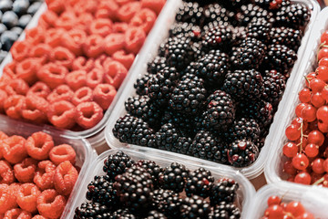 Fresh berries at display on the market stall. Blueberry, raspberry, blackberry.