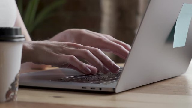 Hands and fingers on the keyboard close-up. Woman working on laptop at home interier. Near the window.