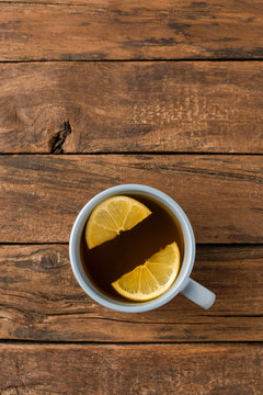 Overhead shot of cup of tea with silce of lemon on white wooden table