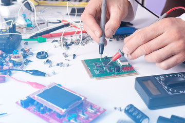 Technician man hands using digital multimeter to check and measure electrical voltage of computer...