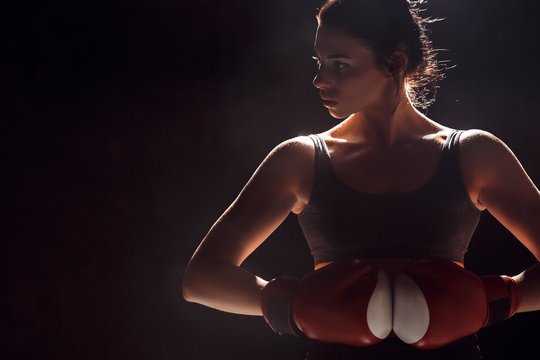 Boxing. Woman Boxer In Gloves Standing On Dark Ring Hands Together Looking Aside Careful