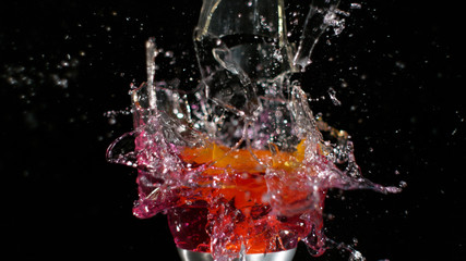 Glass shattering and red liquid spilling out in explosion
