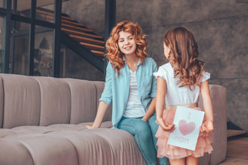 small girl making surprise for mommy to mothers day- holding greeting card behind the back