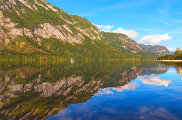 Fototapeta na wymiar Panoramic view of Bohinj Lake with mountain range which reflected in turquoise water. Famous touristic place and travel destination in Europe. Bohinj Lake, Triglav National Park, Slovenia