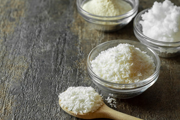 organic coconut shreds in glass bowl along with a spoonful of coconut shreds.