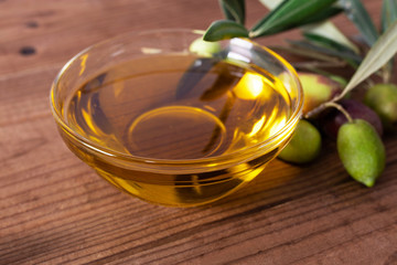bowl of olive oil and olives with olive branches