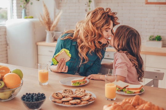 daughter and mother having breakfast and touching noses on the domestic kitchen