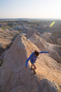 A woman walking along the ridgelines of one of the many beautiful spires in Badlands National Park, South Dakota at dusk. The park has few designated trails allowing visitors to scramble/hike to their hearts content.