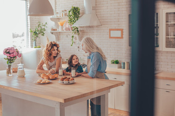 three generations family talking on the kitchen with milk and cookies