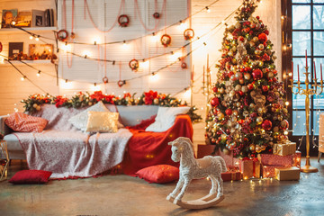 Christmas home decoration: Christmas tree, garlands, sofa, baby horse, polar bear. Christmas decorations in red and gold. Christmas Interier