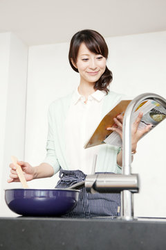 本を見ながら料理をする女性