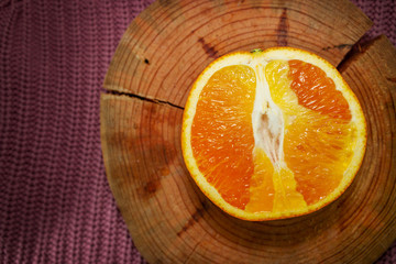 Juicy sliced orange isolated on wooden background. Healthy citrus on warm sweater