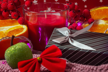 Christmas concept. Bokeh holiday lights. New Year card. Gift box, oranges, decorative apple and bow on warm sweater and red dotted background