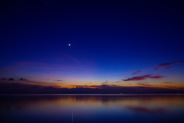 The moon and first star on sky at the lake in the twilight after sunset.