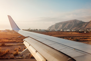 Plane landing in Fira, Santorini island. View of airplane wing. Traveling concept