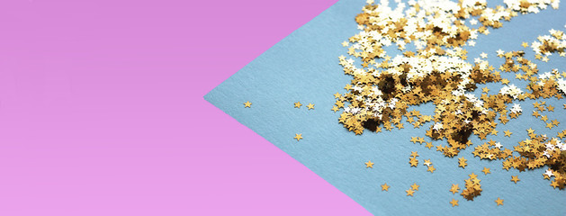 Delicate pink and angular part of trendy blue background with golden glitter stars. Flat lay....