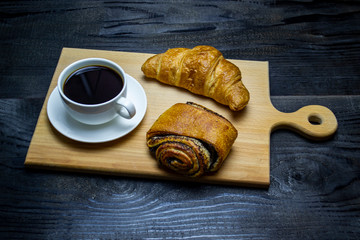 coffee with a mug next to a bun with poppy seeds, top view