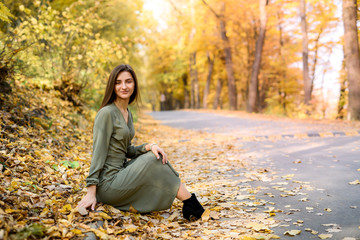 Autumn colours. Beautiful woman in coat posing in forest on roadside