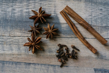 Raw cinnamon barks, cloves and star-anise with a wooden background