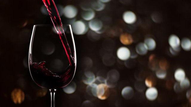 Red wine pouring into glass. Slow motion, new year background