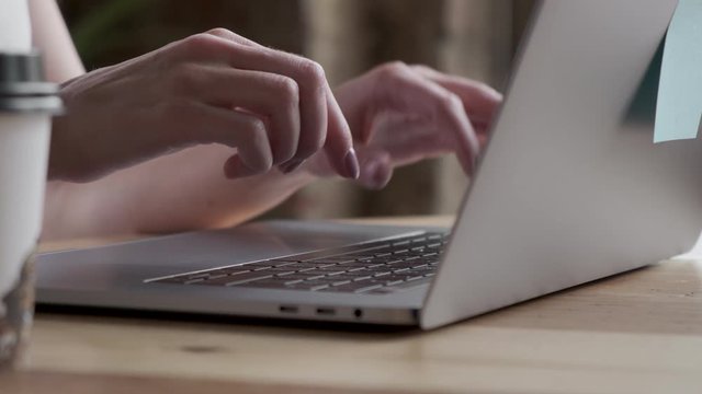 Hands and fingers on the keyboard close-up. Woman working on laptop at home interier. Near the window.