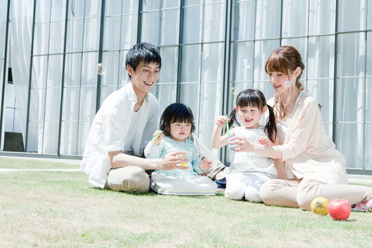 庭でシャボン玉を吹く子供と夫婦