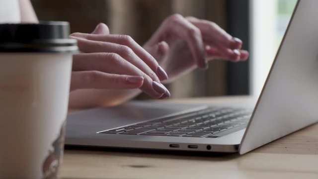 Hands and fingers on the keyboard close-up. Woman working on laptop at home interier. Near the window. 