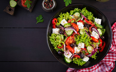 Healthy food. Greek salad with cucumber, tomato, sweet pepper, lettuce, red onion, feta cheese and olives.  Top view, copy space