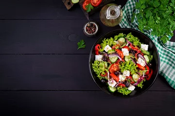 Foto op Canvas Healthy food. Greek salad with cucumber, tomato, sweet pepper, lettuce, red onion, feta cheese and olives.  Top view, copy space © timolina