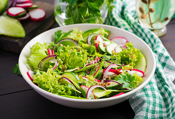 Healthy vegan food. Vegetarian vegetable salad of radish, cucumbers, lettuce  and red onion.