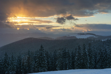 A bright winter in the Ukrainian Carpathian Mountains with snow-capped mountain peaks and picturesque meadows with mountain lodges and hikers.