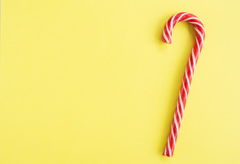 Christmas composition with candy cane on yellow background. Flat lay, copy space.