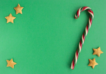 Christmas composition with candy cane, stars  on green background. Flat lay, copy space.