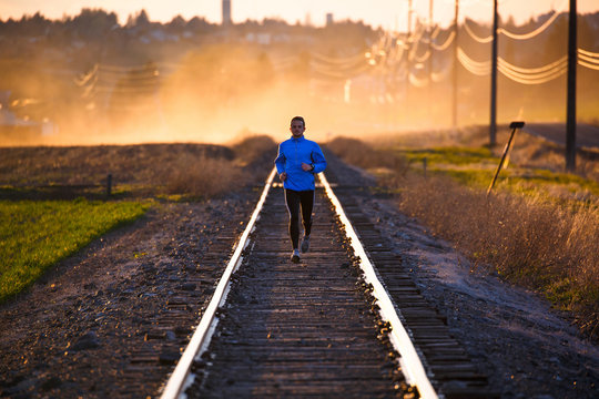 A man on an evening run along abandoned railroad tracks near Pullman, Washington at sunset. The dust cloud is from nearby farming activity.