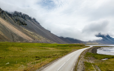 Droga na wybrzeżu, góry w chmurach, krajobraz Islandia
