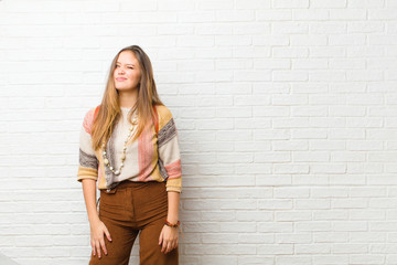 young pretty woman looking happy and friendly, smiling and winking an eye at you with a positive...