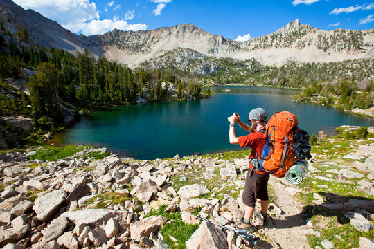 A man akes video with his camera at Hourglass Lake one of the many beautiful Boulder Chain Lakes in the White Cloud Mountains in Idaho.