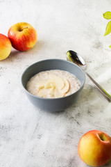 Oatmeal porridge or porridge oats or breakfast cereals with apple isolated on white marble background. Homemade food. Tasty breakfast. Selective focus. Vertical photo.
