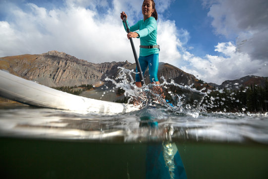 A woman paddle boards on an inflatable SUP at Alta Lakes near Telluride, Colorado in autumn in the San Juan Mountains.