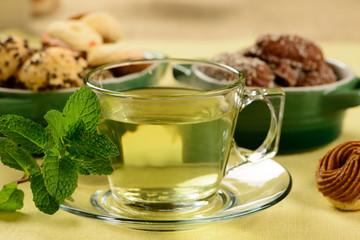 mint tea in transparent cup with sweet cookies around