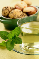 mint tea in transparent cup with sweet cookies around