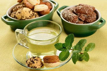 mint tea in transparent cup with sweet cookies around