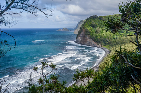 Gorgeous view overlooking waves breaking on Pololu Valley Beach (a black sand beach) below lush cliffs on a windy day, Big Island, Hawaii, USA
