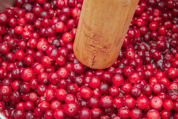 Crush the red cranberry berries with a wooden rolling pin