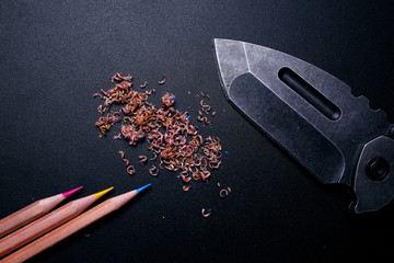 pencil and knife on black background